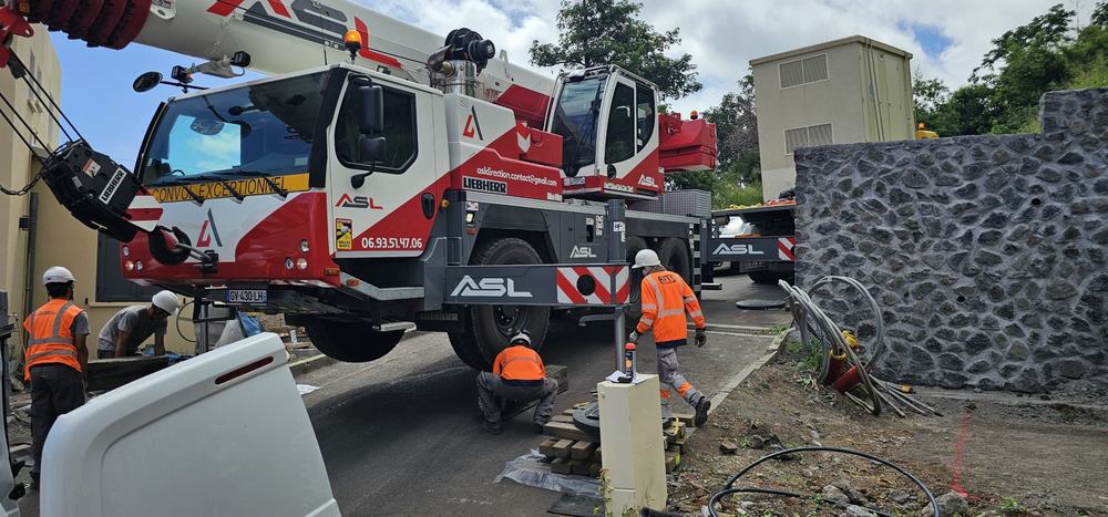 Équipe ASL calant les stabilisateurs d’une grue mobile sur une voie en forte pente