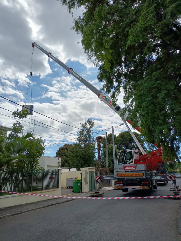 Grue mobile en rue résidentielle levant une unité de climatisation
